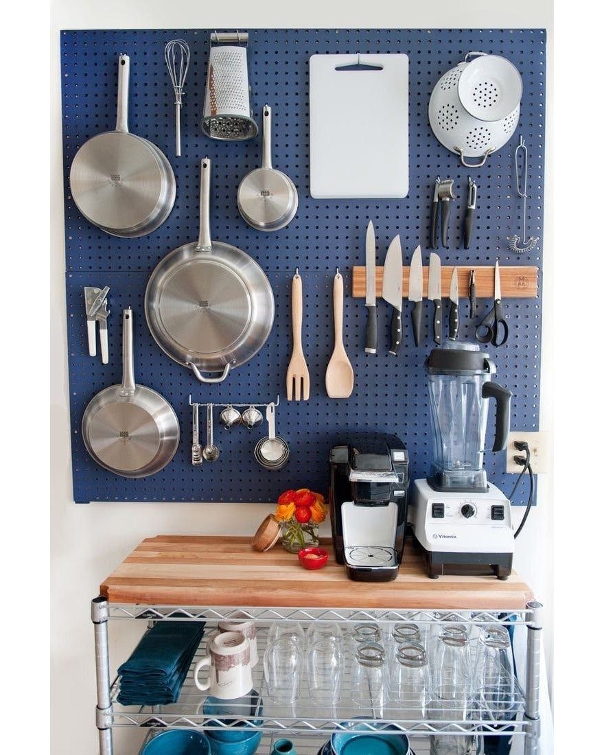 22 Apt Kitchen Ideas to Maximize Style and Function 14 Blue pegboard with hanging cookware and kitchen tools above a wooden countertop shelf