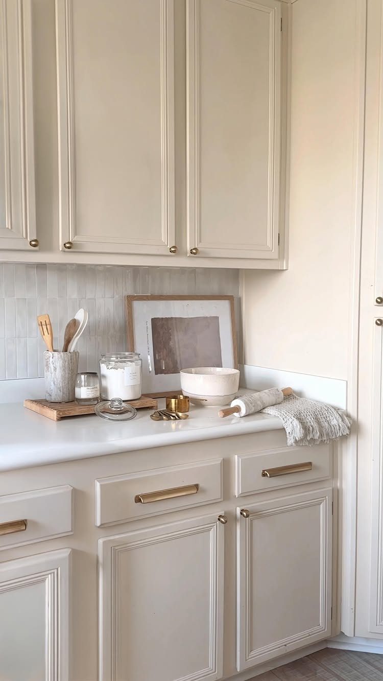 22 Apt Kitchen Ideas to Maximize Style and Function 8 Cream kitchen cabinets with gold hardware and white countertops in a bright setting.