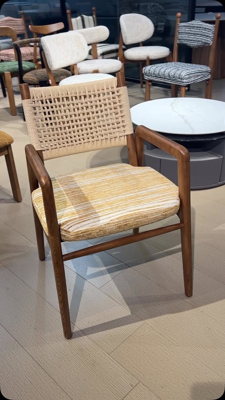 Wooden dining chair with woven cane back and striped fabric seat in showroom