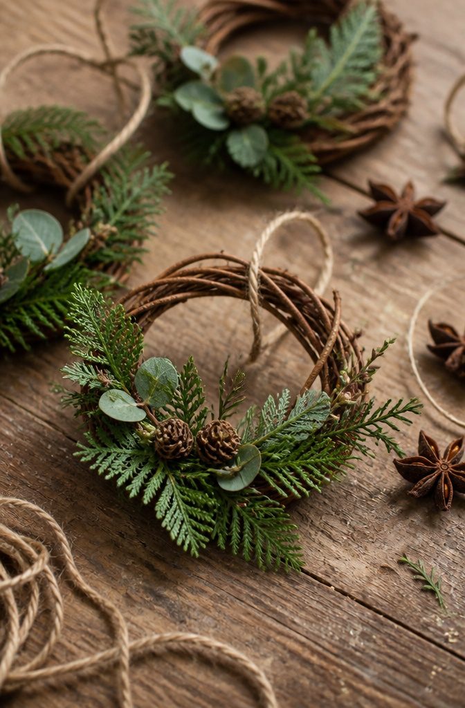 Mini wreath ornaments made of greenery displayed on a Christmas tree.