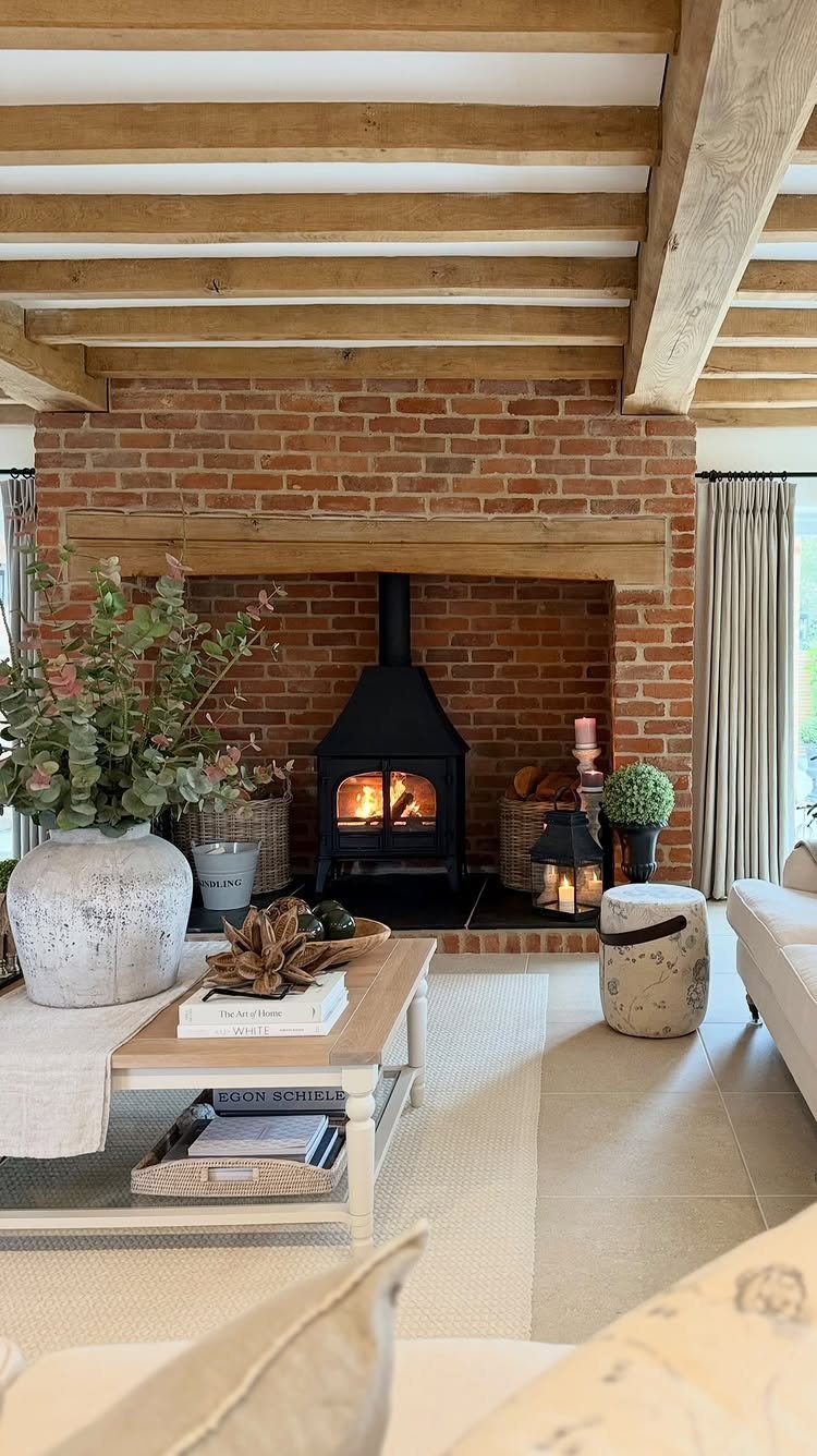 Rustic living room with a brick fireplace, wood stove, and exposed ceiling beams.