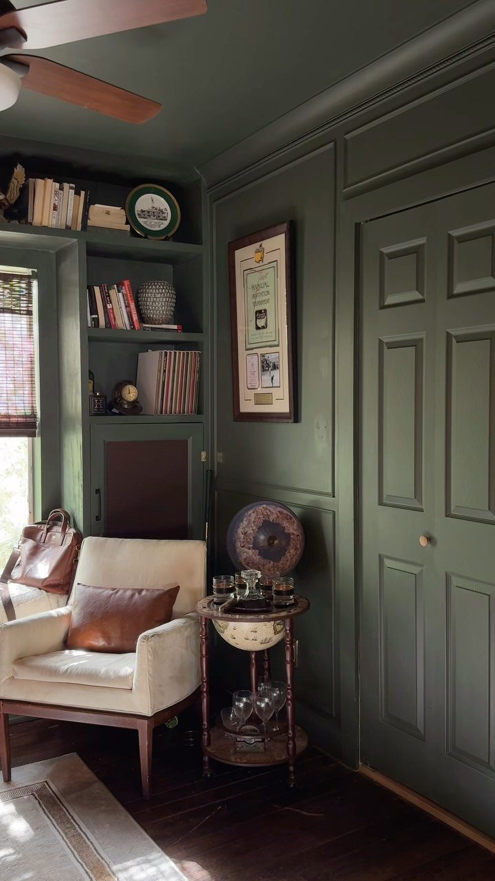 Dark green paneled walls and ceiling in a room with a cream armchair.
