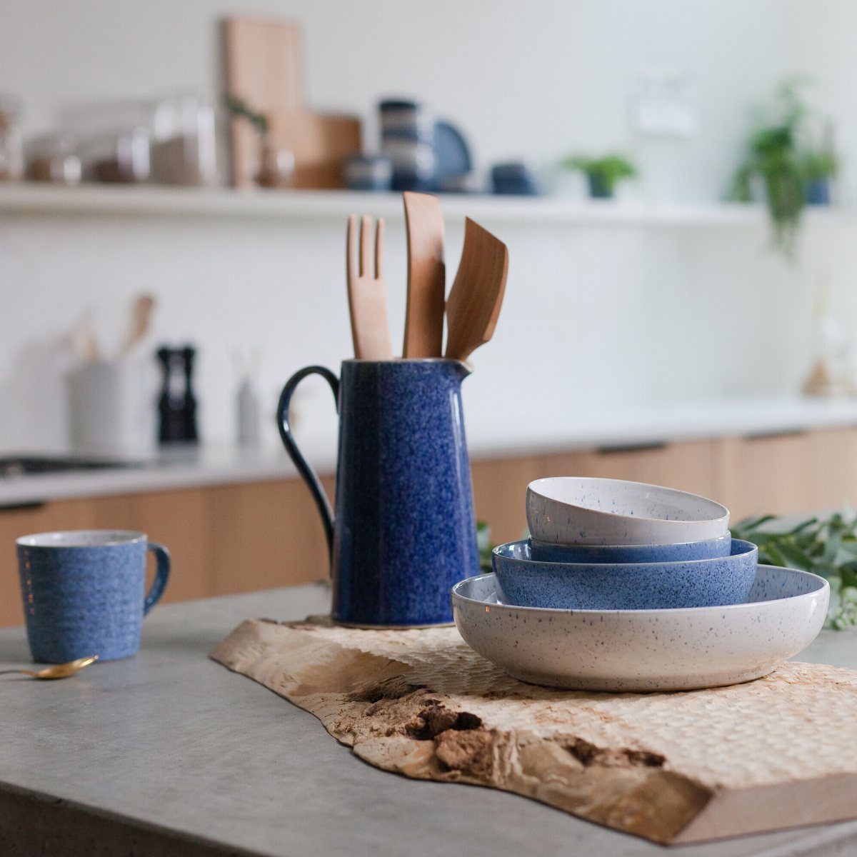 Denby Dinnerware Sets in 5 Classic Styles 3 Blue and white speckled ceramic dinnerware set with wooden utensils on a countertop.