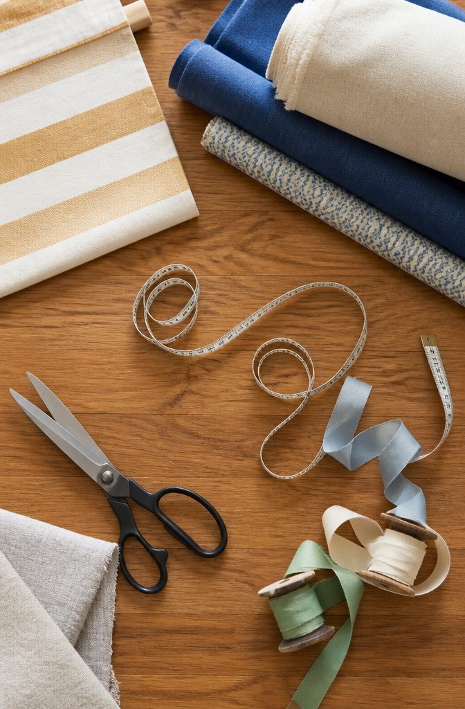 Medium-weight fabric, scissors, and supplies for DIY window shades.