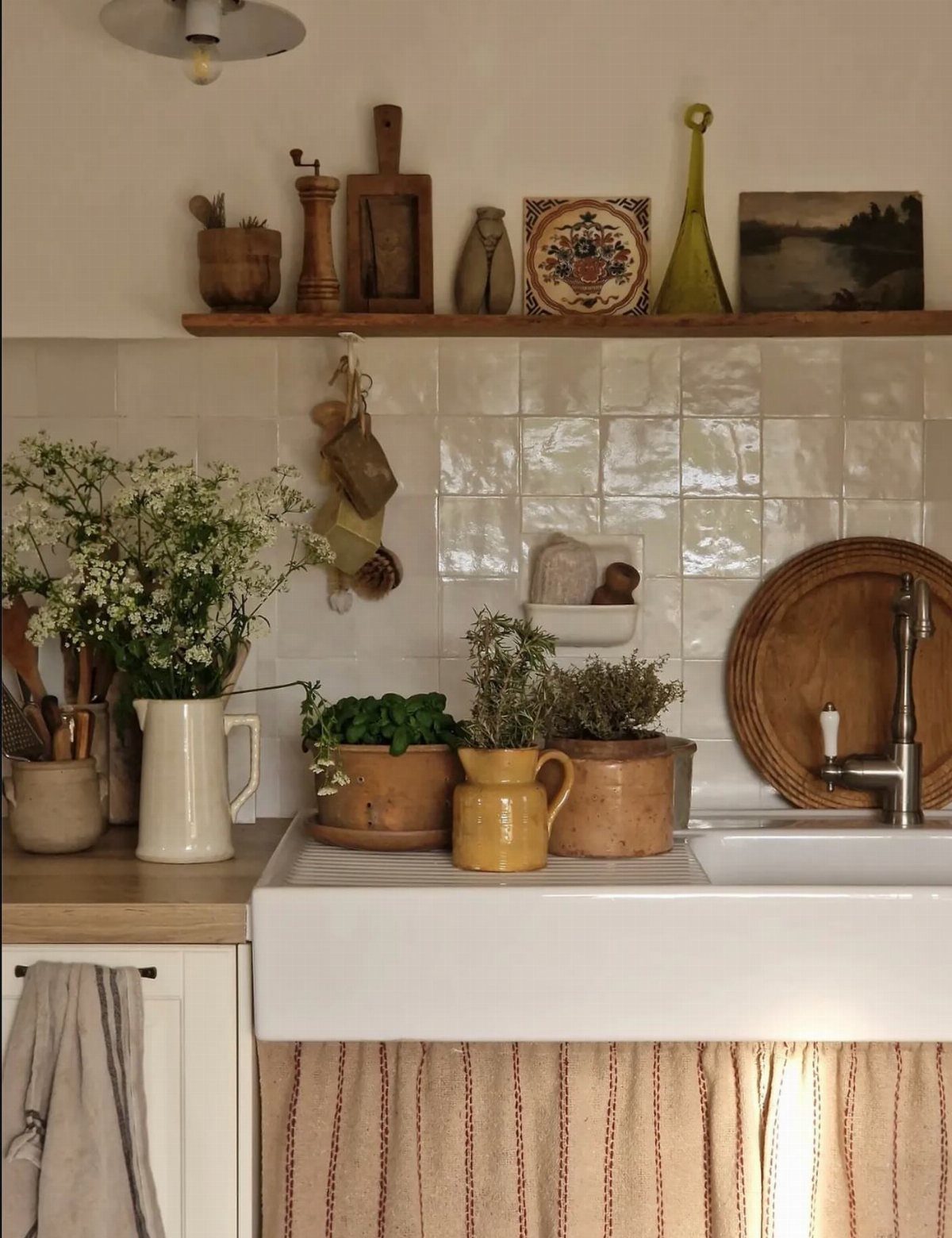 Rustic kitchen with white farmhouse sink and a wooden shelf of decorative objects.