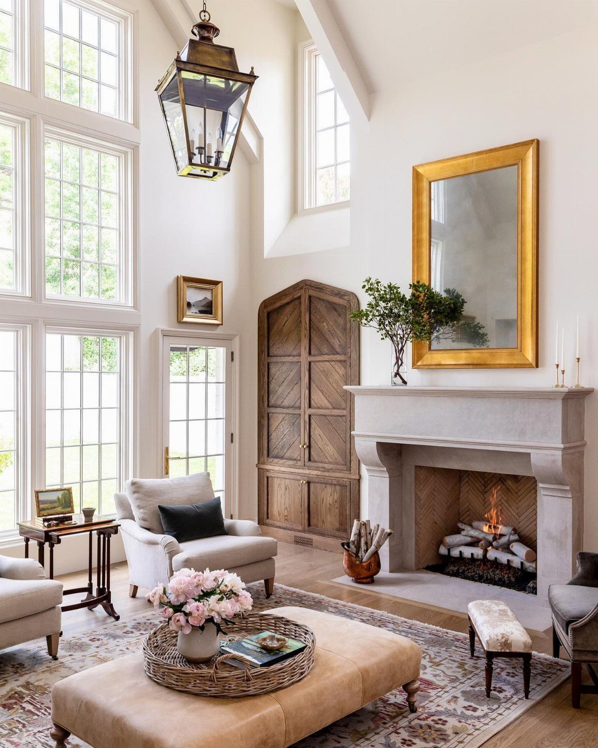 Stone fireplace with burning logs in a bright, neutral European style living room.