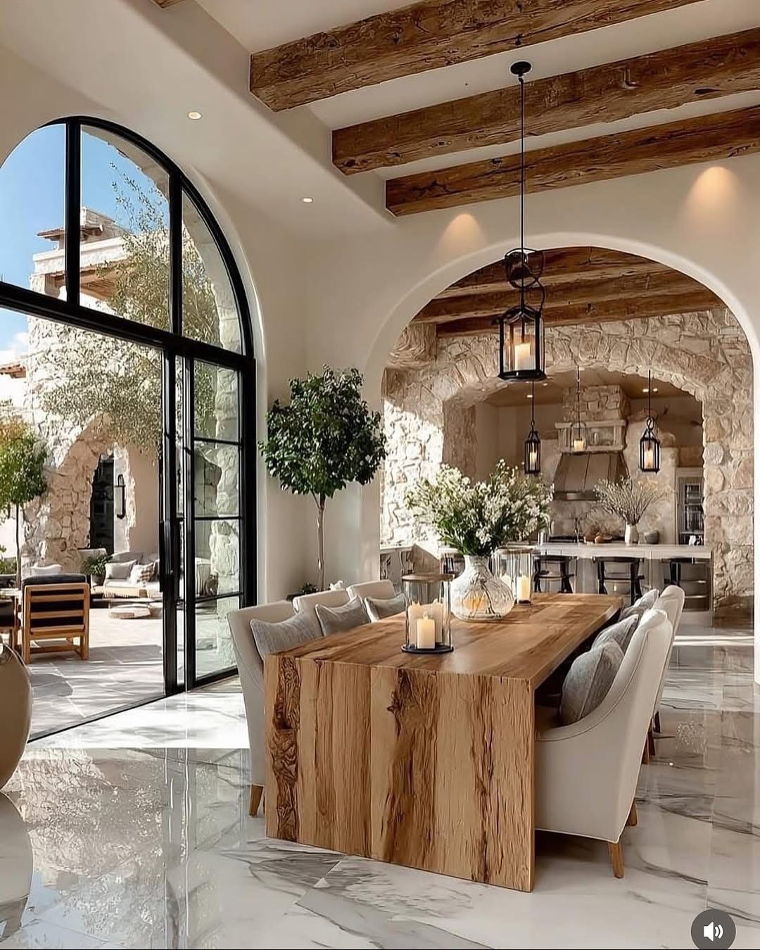Dining room with a large wooden table, marble floors, and exposed ceiling beams.