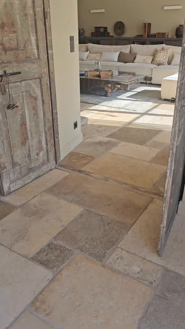 Natural stone floor tiles in beige and tan leading into a bright living room.