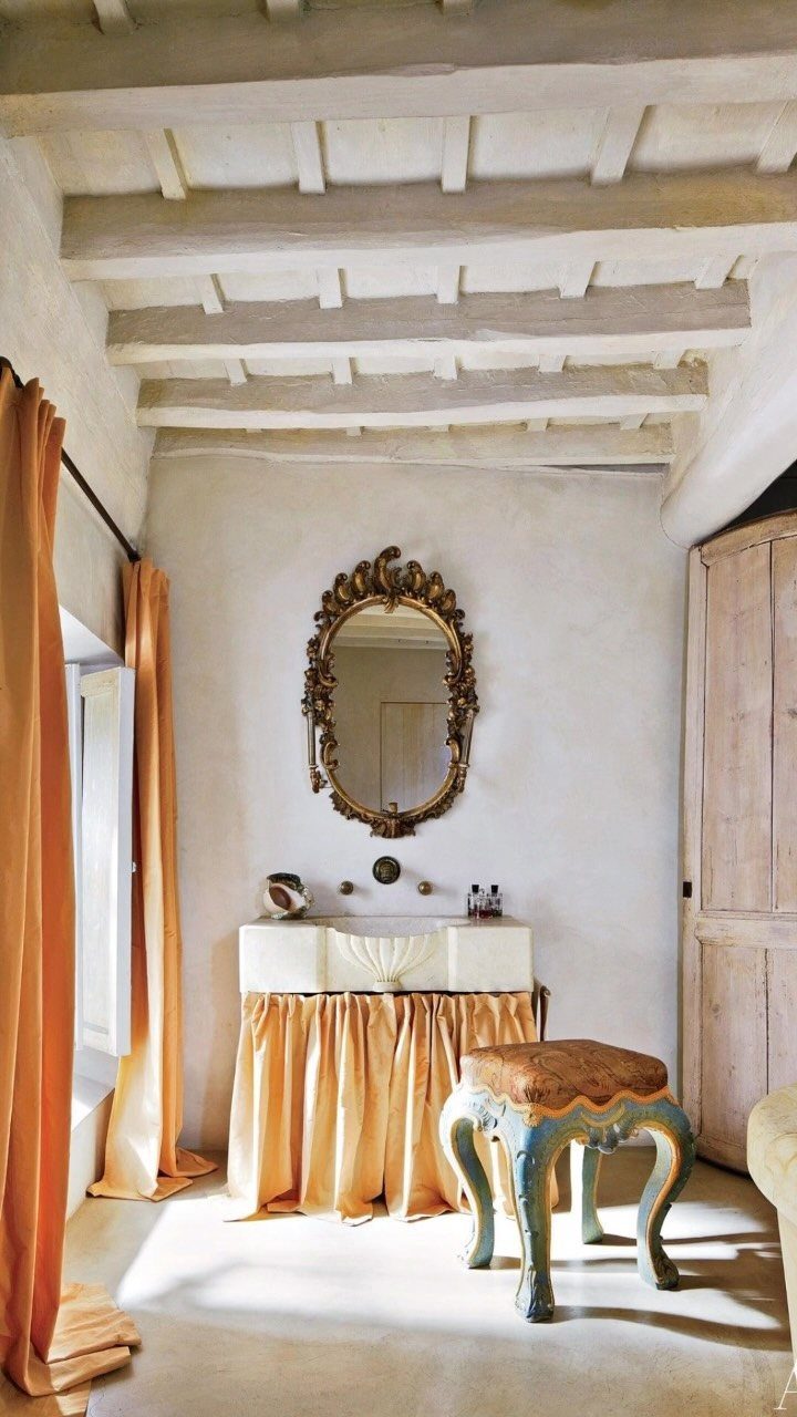 Rustic room with neutral walls, gold mirror, and bold orange and yellow accents.