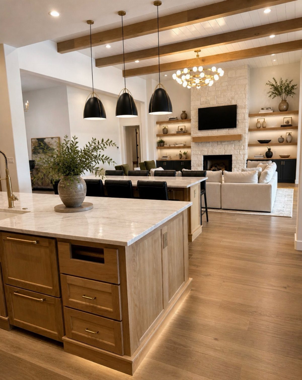 Open-plan interior with marble kitchen island, wooden ceiling beams, and a stone fireplace.