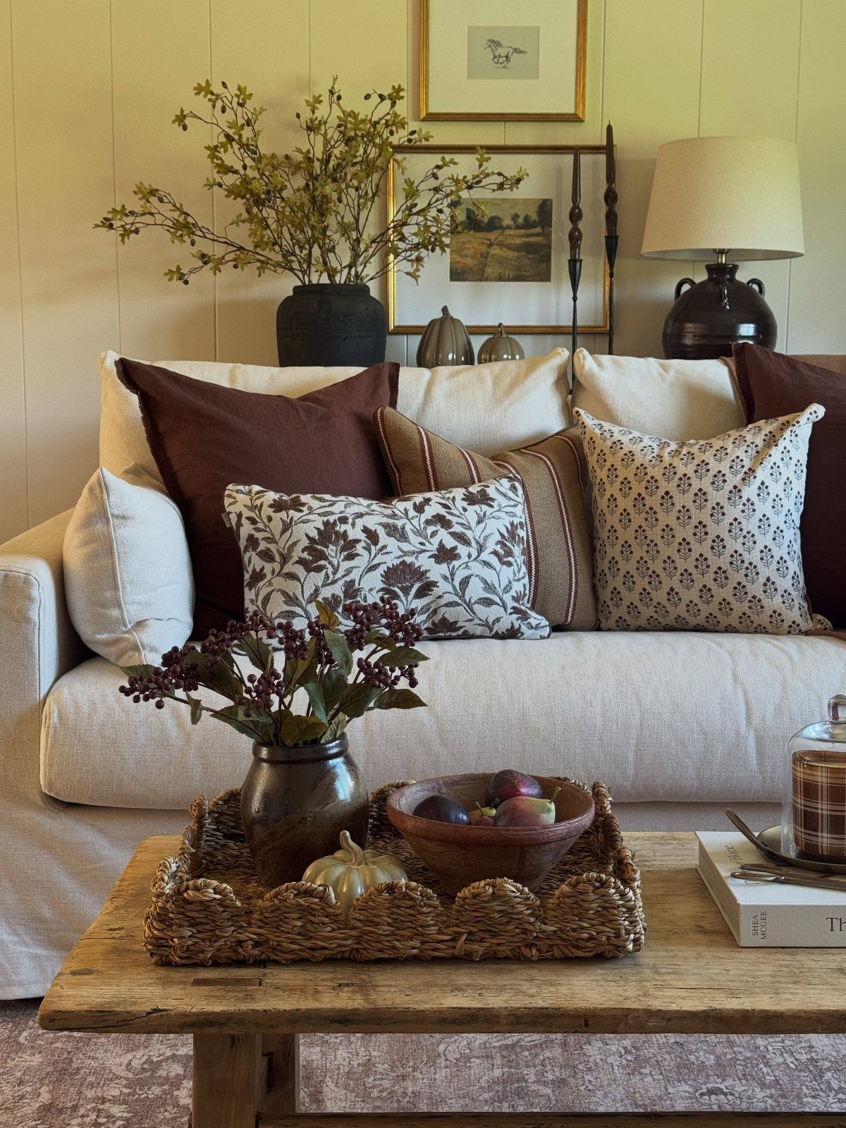 Cream neutral sofa with rich brown and patterned cushions and a rustic wooden table.