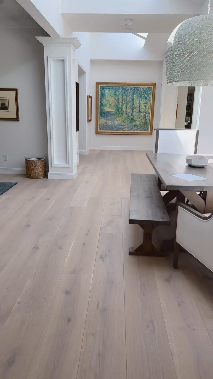 Light-toned wide plank wooden flooring and matching dining table in a bright room