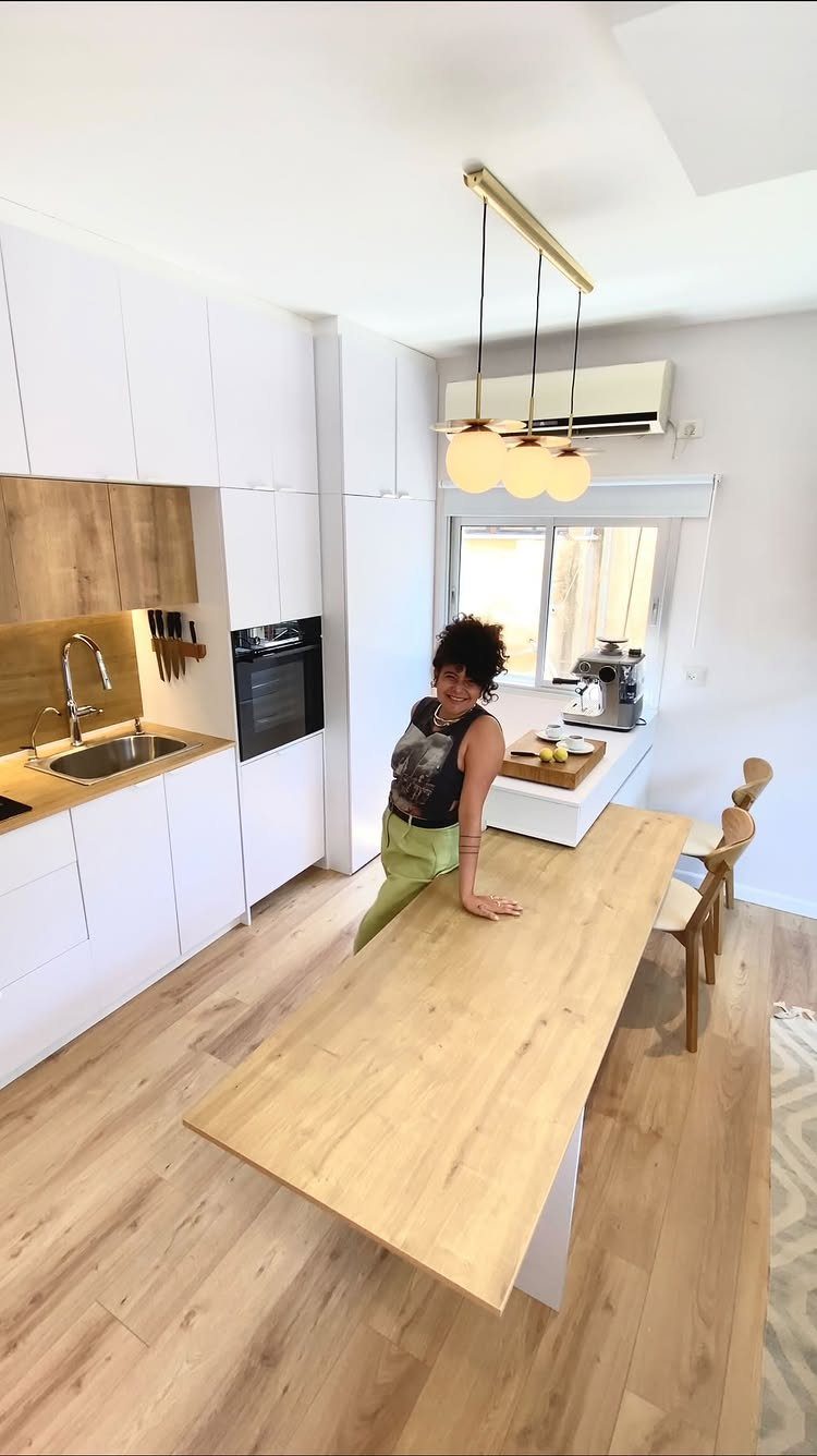 Extendable Kitchen Table Designs: 16 Ideas with Photos 4 Woman leaning on a light wood table extending from a white kitchen island.