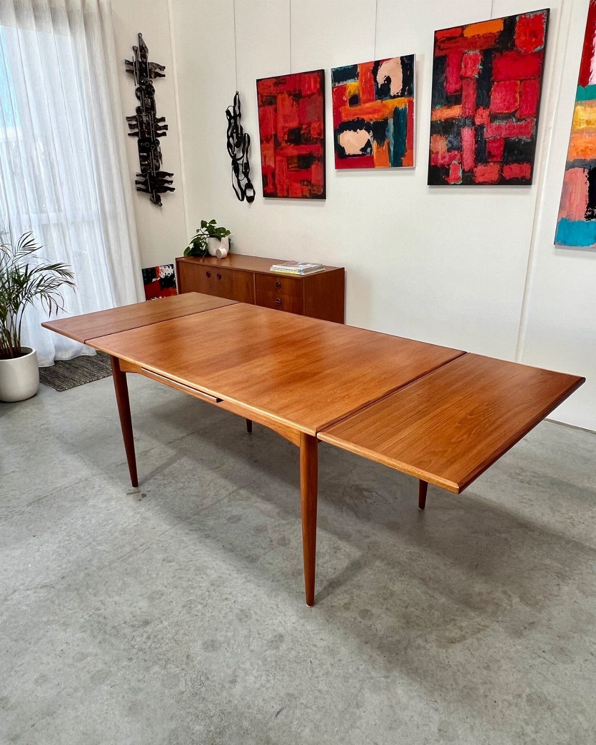 Extendable Kitchen Table Designs: 16 Ideas with Photos 6 Rectangular wooden dining table with extended leaves in a bright room with art.