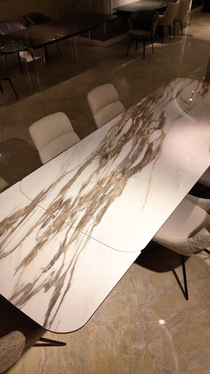 Extendable Kitchen Table Designs: 16 Ideas with Photos 9 Marble-look dining table with gold veining and light upholstered chairs in a showroom.
