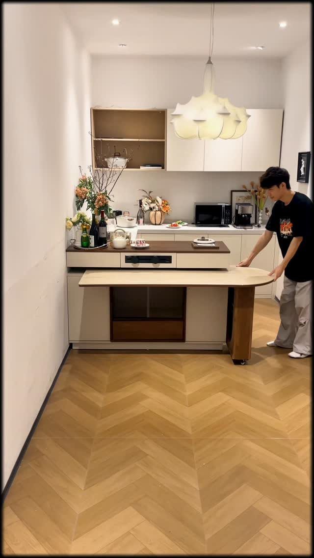 Extendable Kitchen Table Designs: 16 Ideas with Photos 11 Man pulling out a wooden table surface from a white kitchen island.