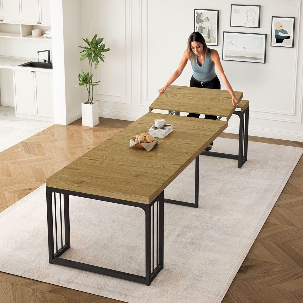 Extendable Kitchen Table Designs: 16 Ideas with Photos 3 Woman inserting a wooden leaf into a rectangular dining table with black metal legs.