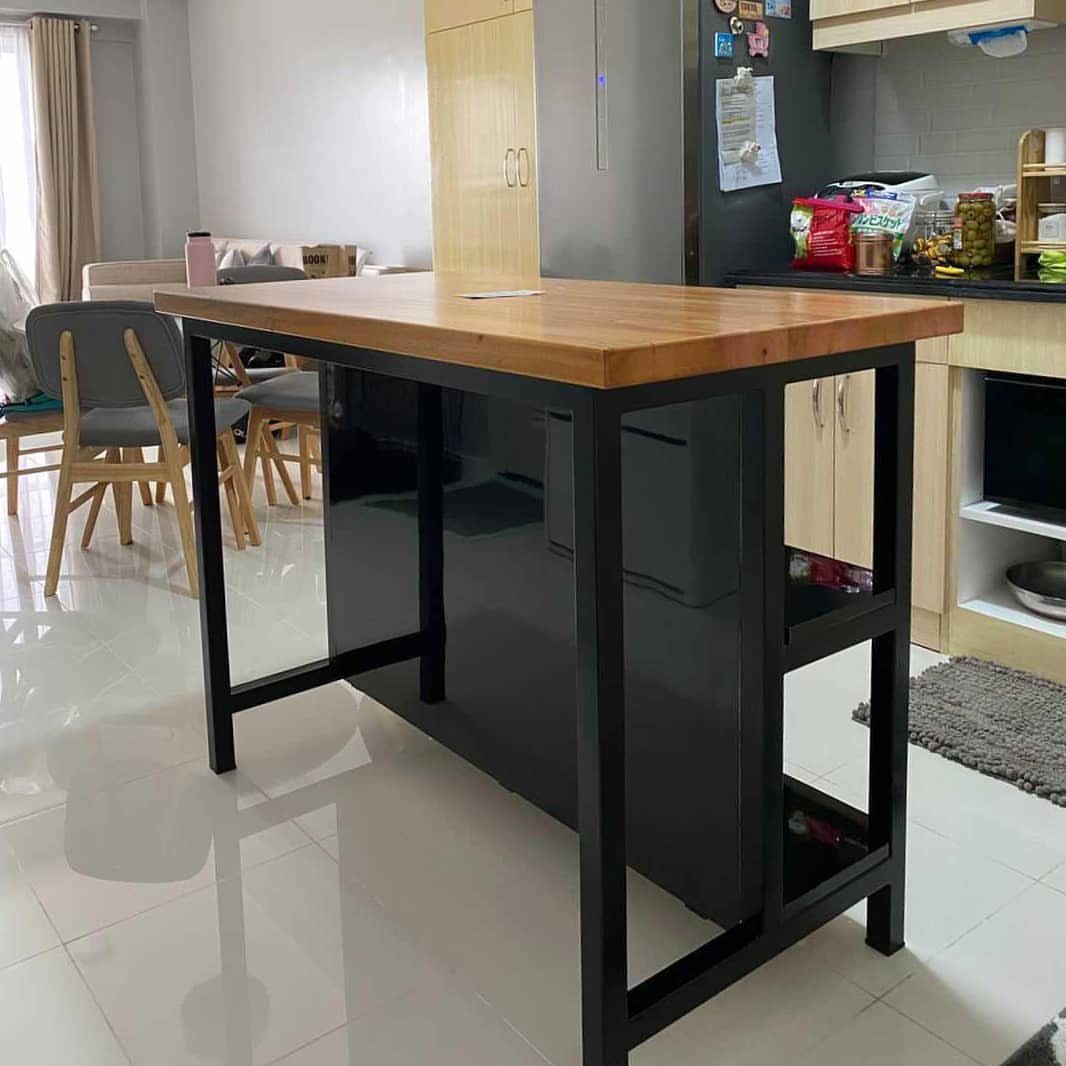 Wooden bar table with black metal legs and grey chairs in a kitchen.