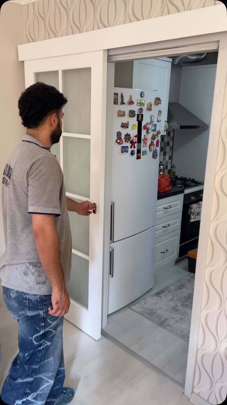 White sliding door with frosted glass panels opening into a small white kitchen.