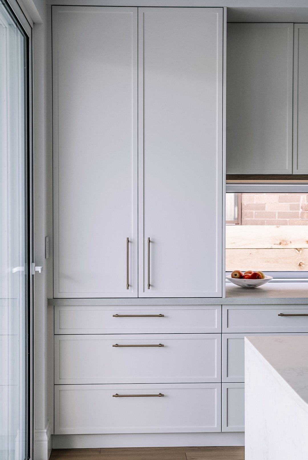 White shaker cabinet doors with slim gold handles in a modern kitchen setting.
