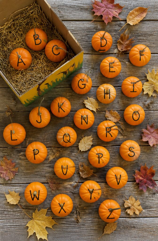 Mini pumpkins with Sharpie letters on their ridges.