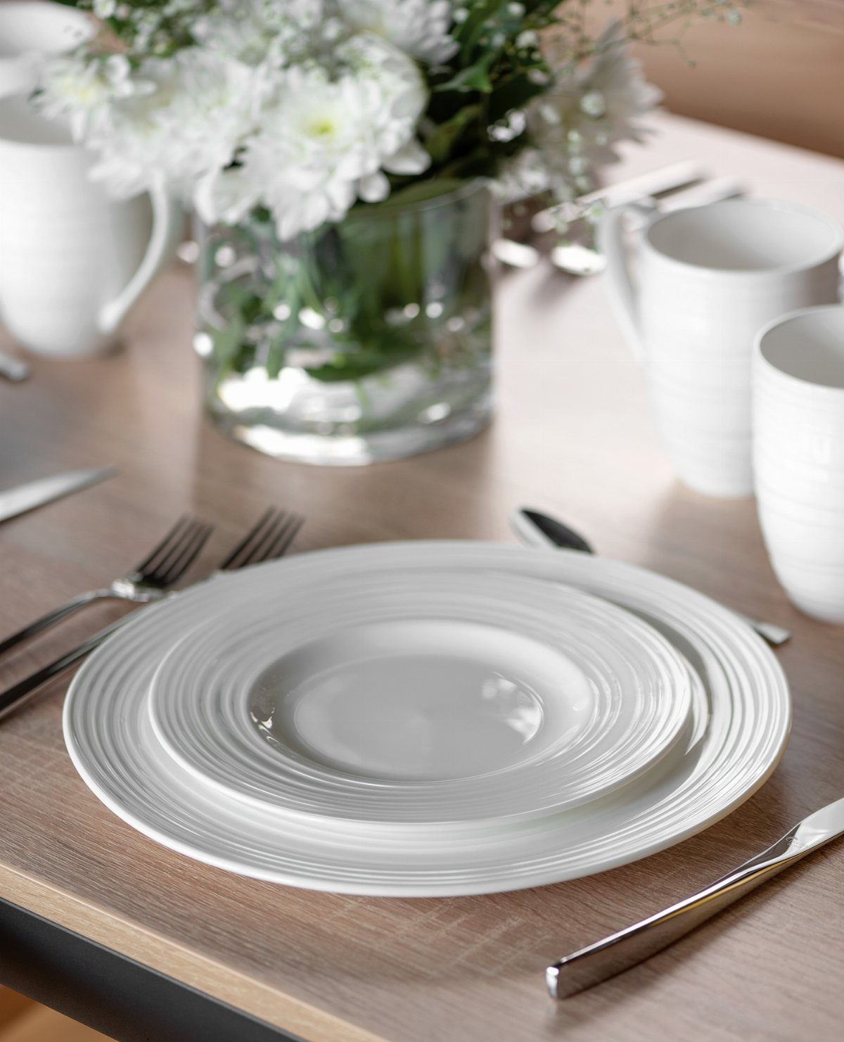 Fancy Dinnerware Set Ideas for 2026 Tables (28 Styles) 2 Stacked white porcelain plates with concentric ridges on a light wooden dining table.