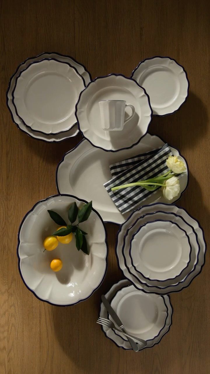 Fancy Dinnerware Set Ideas for 2026 Tables (28 Styles) 28 White scalloped dinnerware set with blue rims on a wooden table with lemons.