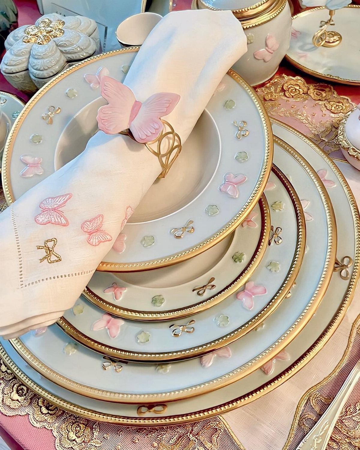 Fancy Dinnerware Set Ideas for 2026 Tables (28 Styles) 5 White porcelain plates with gold rims and pink butterfly patterns and a matching napkin.