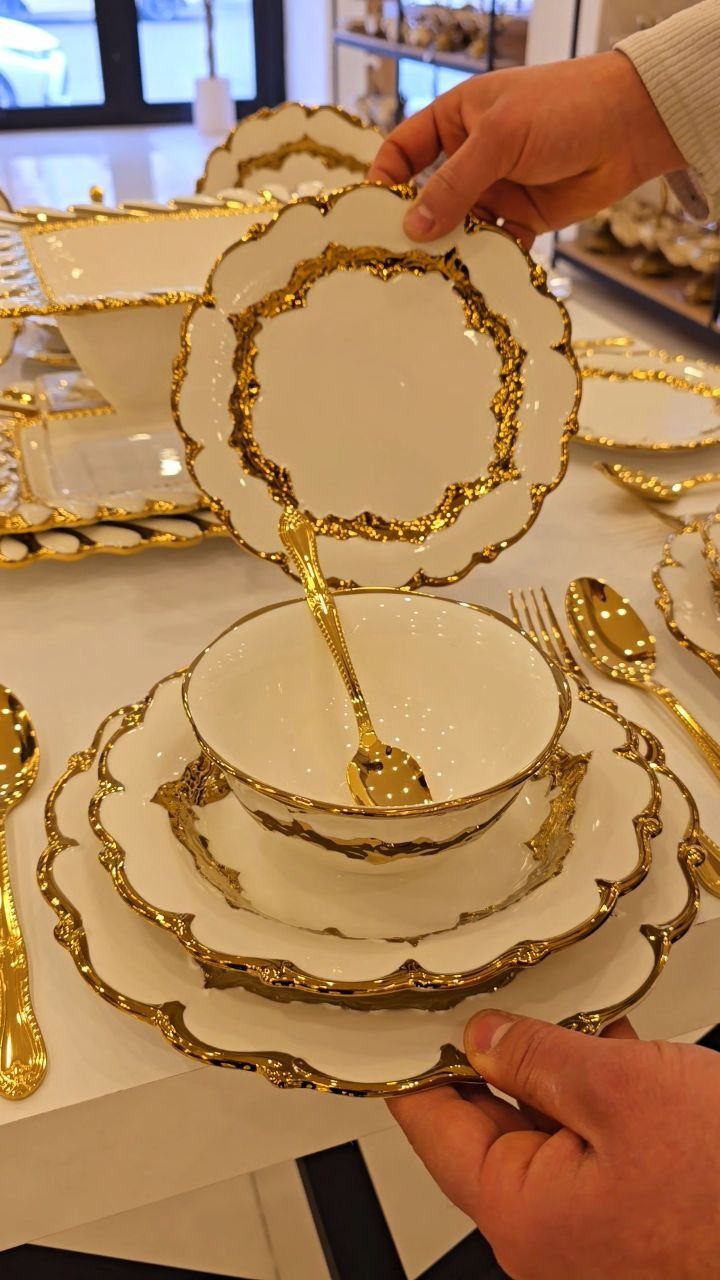 Fancy Dinnerware Set Ideas for 2026 Tables (28 Styles) 6 White porcelain dinnerware with ornate scalloped gold rims and matching gold cutlery.