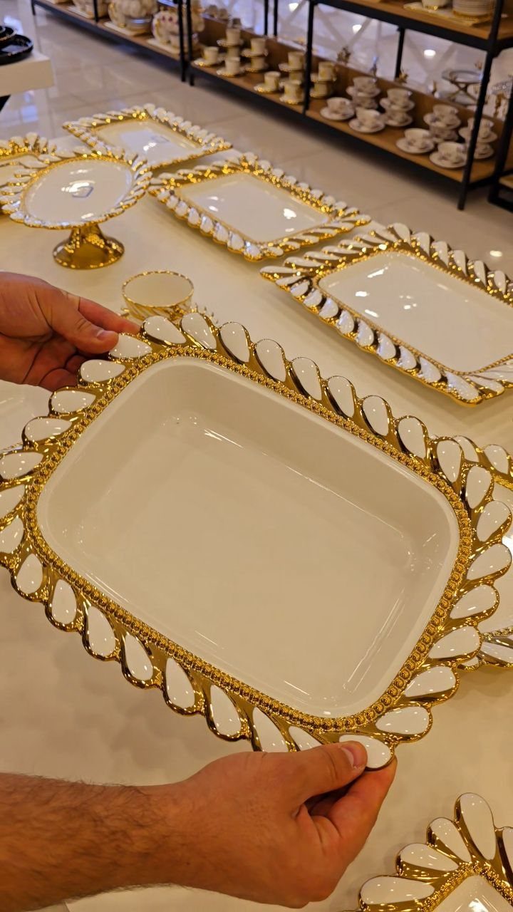 Fancy Dinnerware Set Ideas for 2026 Tables (28 Styles) 9 Ornate white ceramic platter with gold trim held by hands in a store