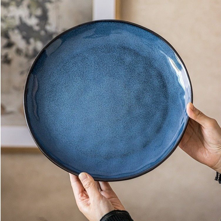 Fancy Dinnerware Set Ideas for 2026 Tables (28 Styles) 18 Deep blue ceramic plate with a matte finish held by two hands.