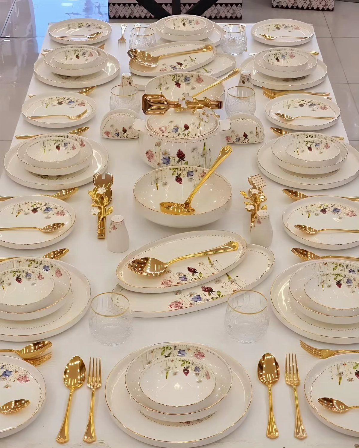 Fancy Dinnerware Set Ideas for 2026 Tables (28 Styles) 29 Floral dinnerware set with gold rims and gold cutlery arranged on a white table.