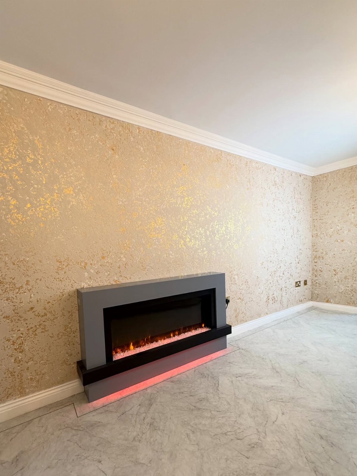 9 Gold Accent Living Room Ideas for Every Style 7 Gold-flecked wallpaper wall with a modern grey electric fireplace and marble flooring