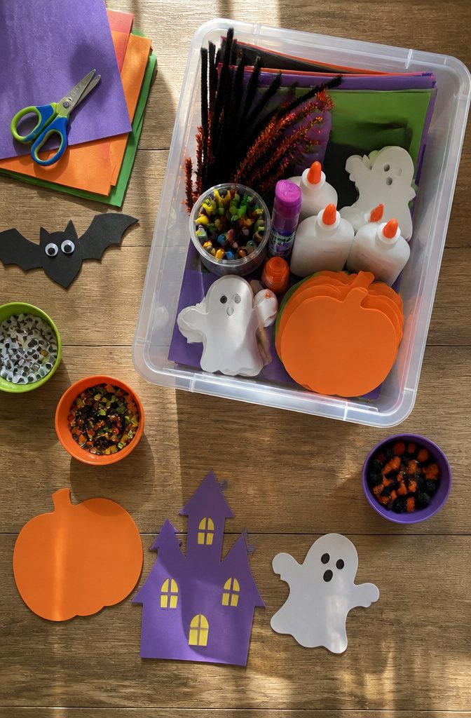 Crafting supplies including construction paper, glue, scissors, and markers in a bin.