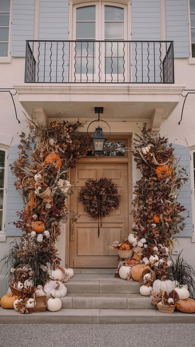 Wooden front door with a covered entrance decorated with autumn pumpkins and foliage.