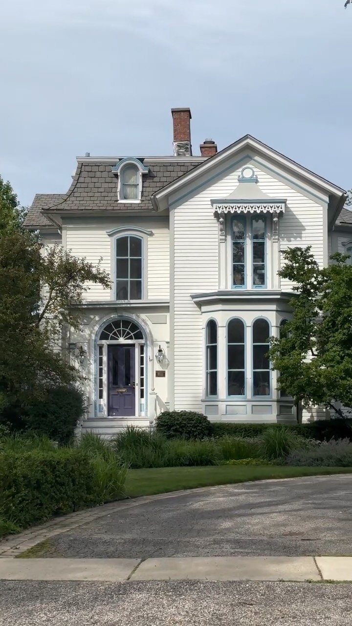 White house with blue trim featuring a small dormer window on the roof.