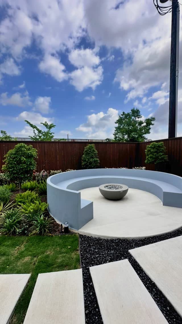 Curved blue concrete outdoor seating area with a central fire pit and modern landscaping.
