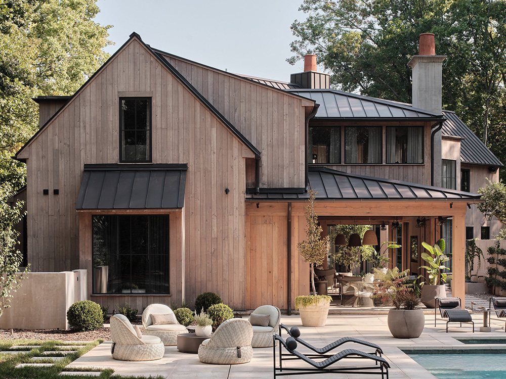 Modern wood-sided house with a dark metal roof and luxury poolside lounge area.