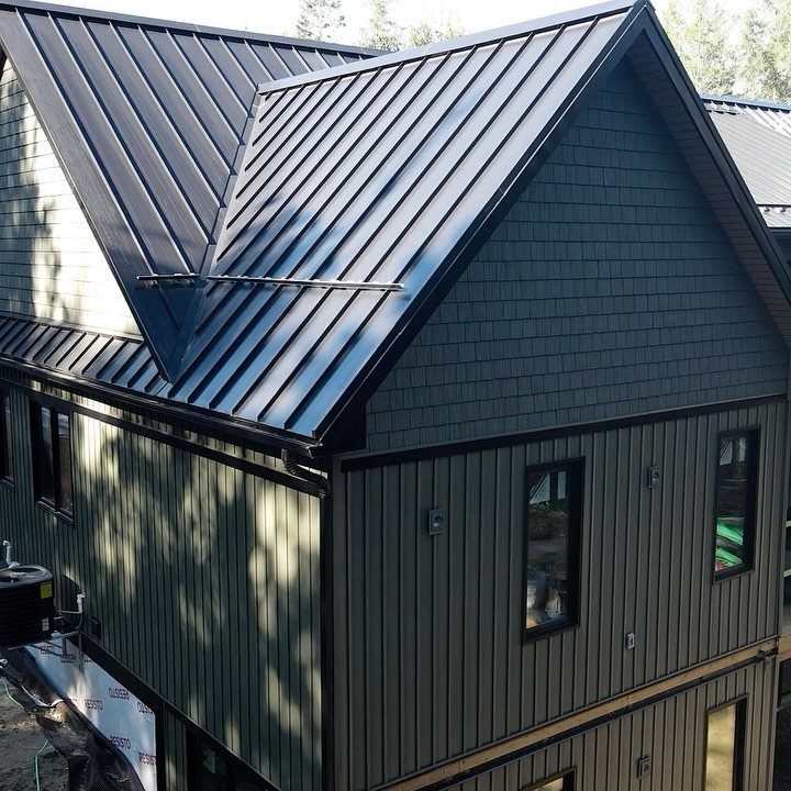 Modern house with dark gray vertical steel siding and a standing seam metal roof.