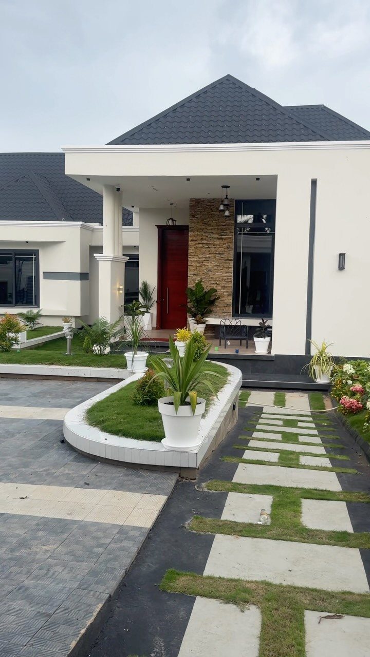 Modern white house exterior with stone veneer accent wall and landscaped walkway.