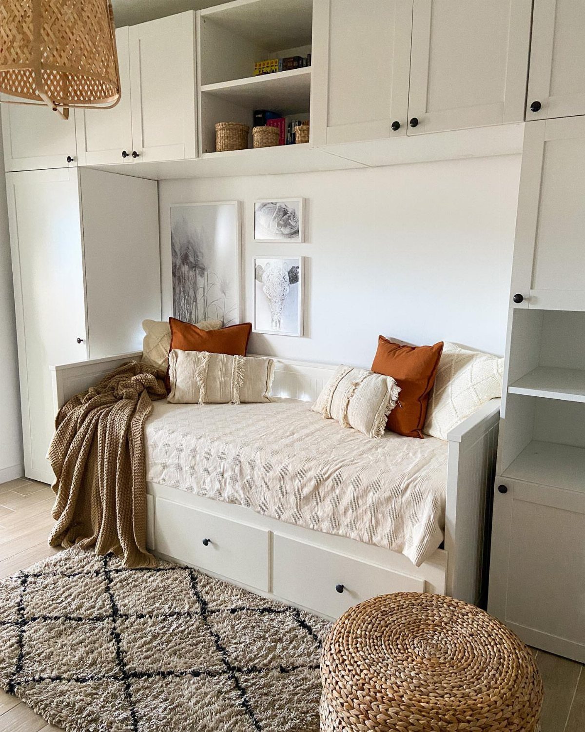 White modular cabinets framing a cozy built-in daybed with orange accent pillows.
