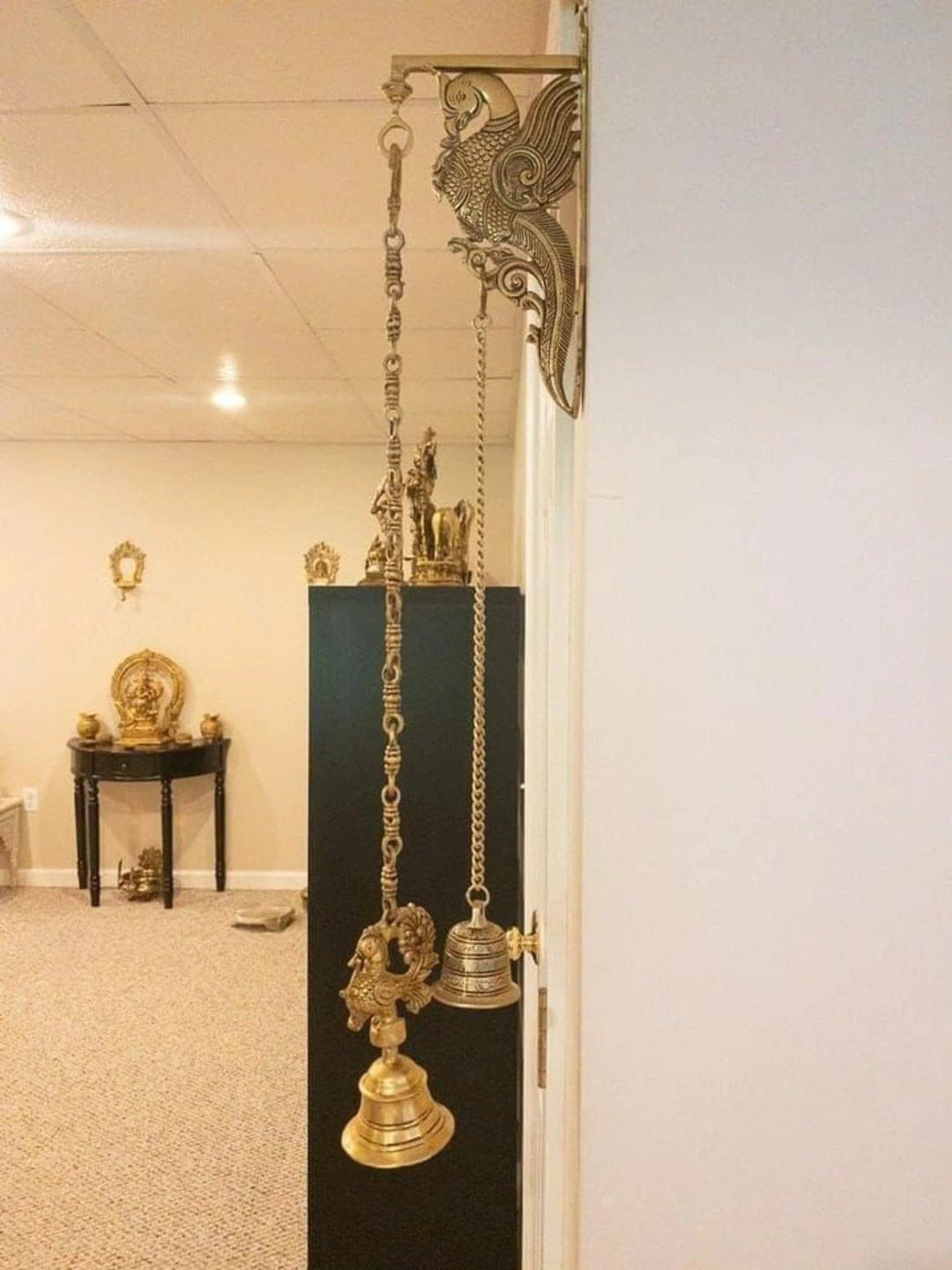 Indian Room Decor: 37 Ideas From Textiles to Wall Hangings 29 Brass bells hanging from a decorative bird bracket on a white wall