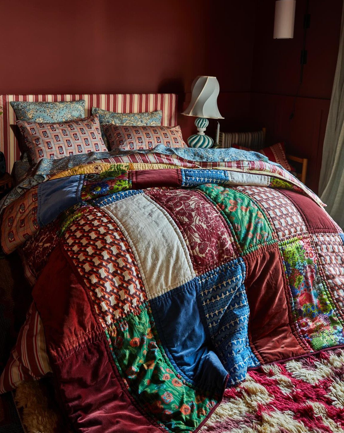 Indian Room Decor: 37 Ideas From Textiles to Wall Hangings 37 Colorful patchwork quilt and patterned pillows on a bed against a red wall