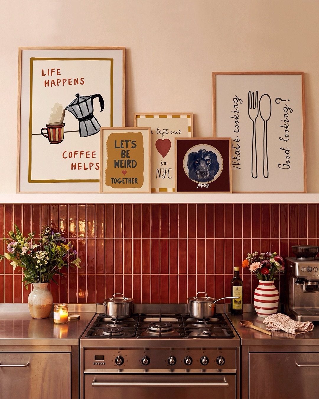 14 Kitchen Tabletop Decor Ideas to Style Your Counters 12 Framed art prints on a pink wall above a red tiled kitchen backsplash.