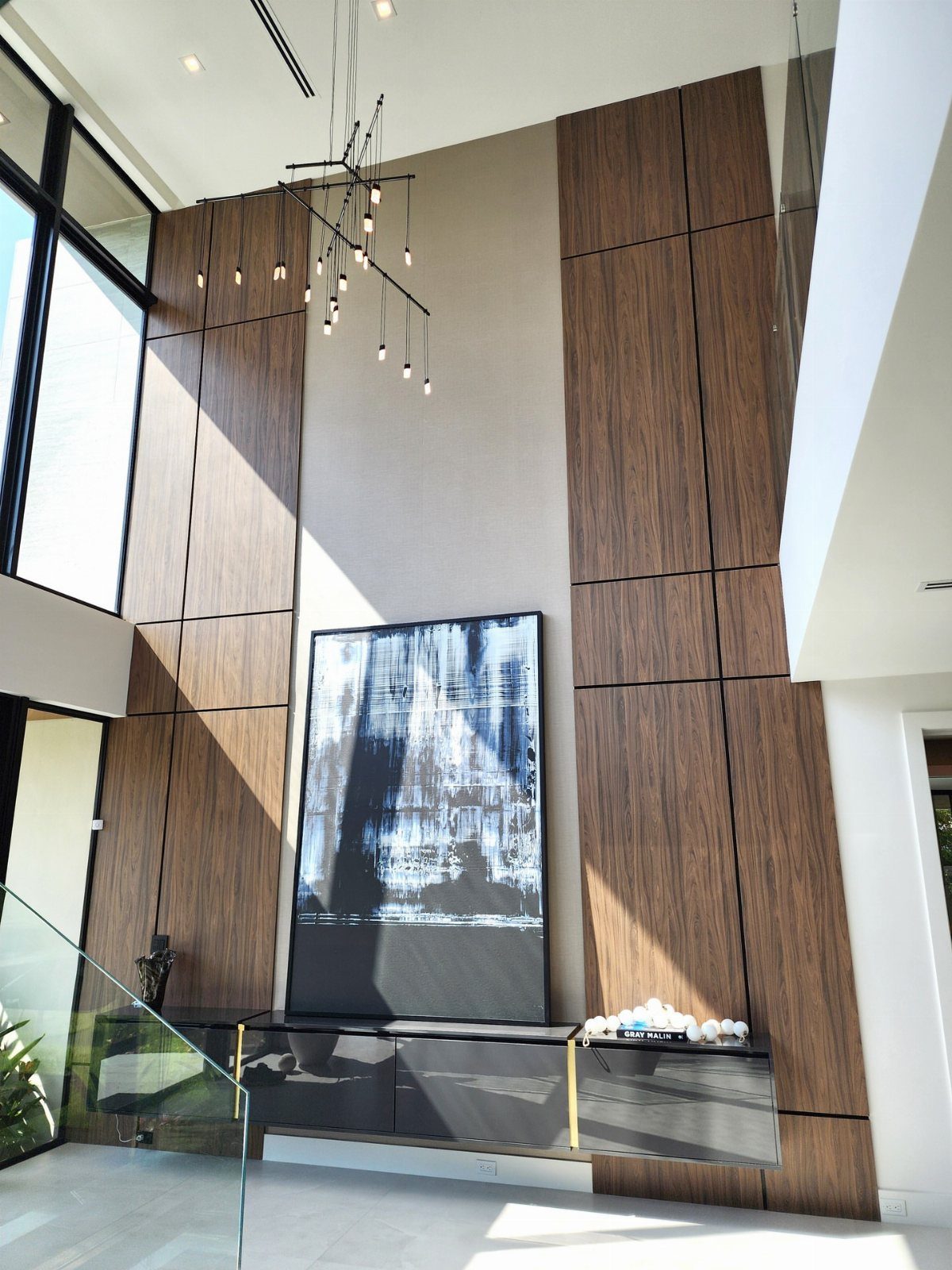 Modern living room with tall wood wall panels and a floating grey cabinet.