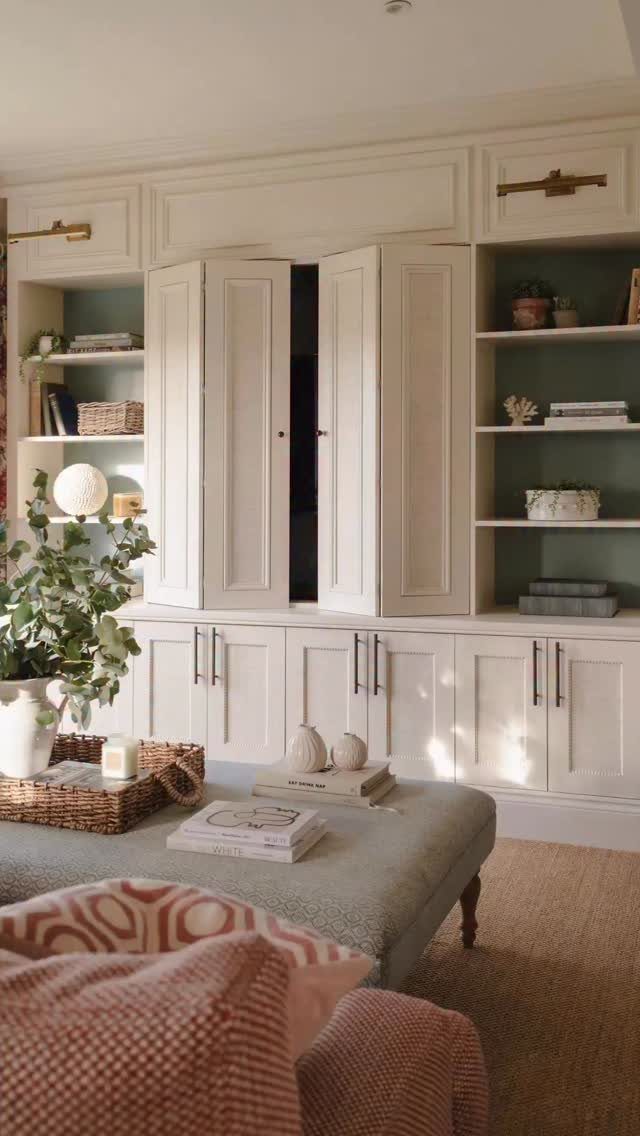 Cream built-in wall unit with cabinet doors partially open to reveal a hidden television.