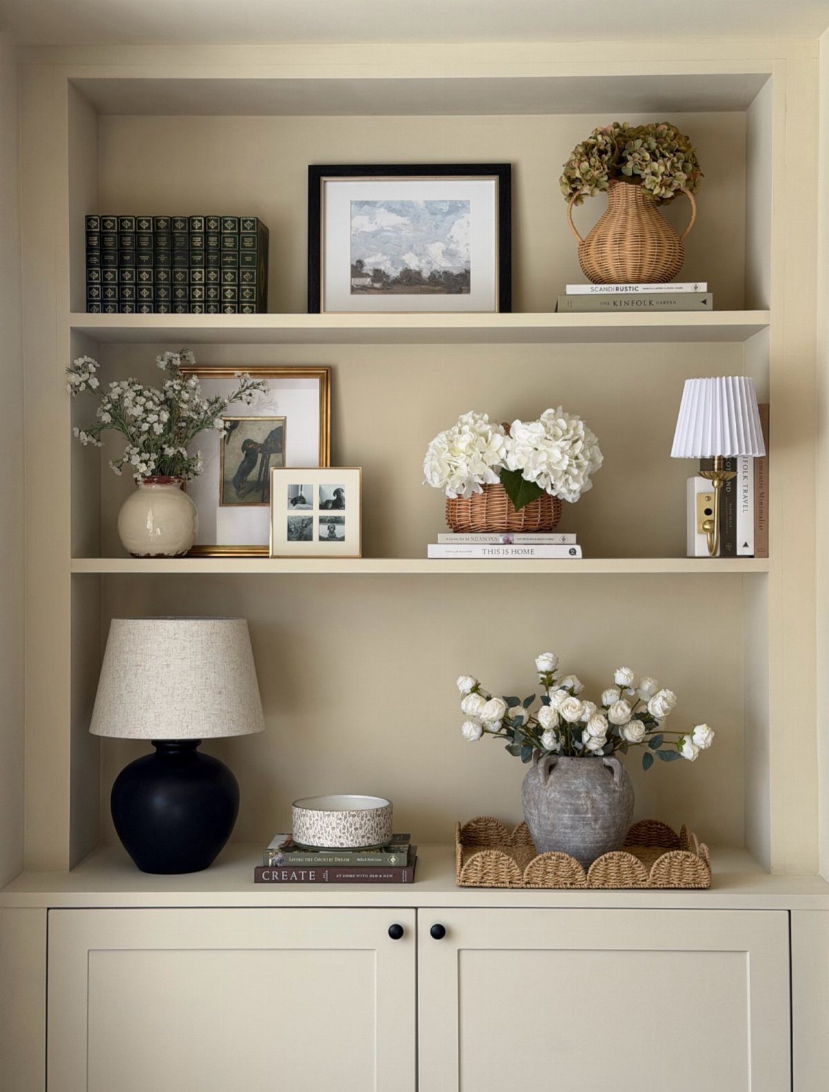 Cream built-in shelves with a three-object grouping of a lamp, bowl, and vase.