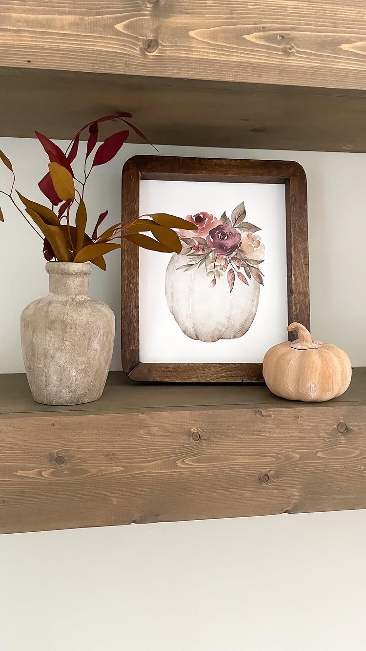 12 Modern Farmhouse Wall Decor Ideas for Living Room 9 Wooden floating shelves decorated with a pumpkin painting, vase, and small pumpkin.