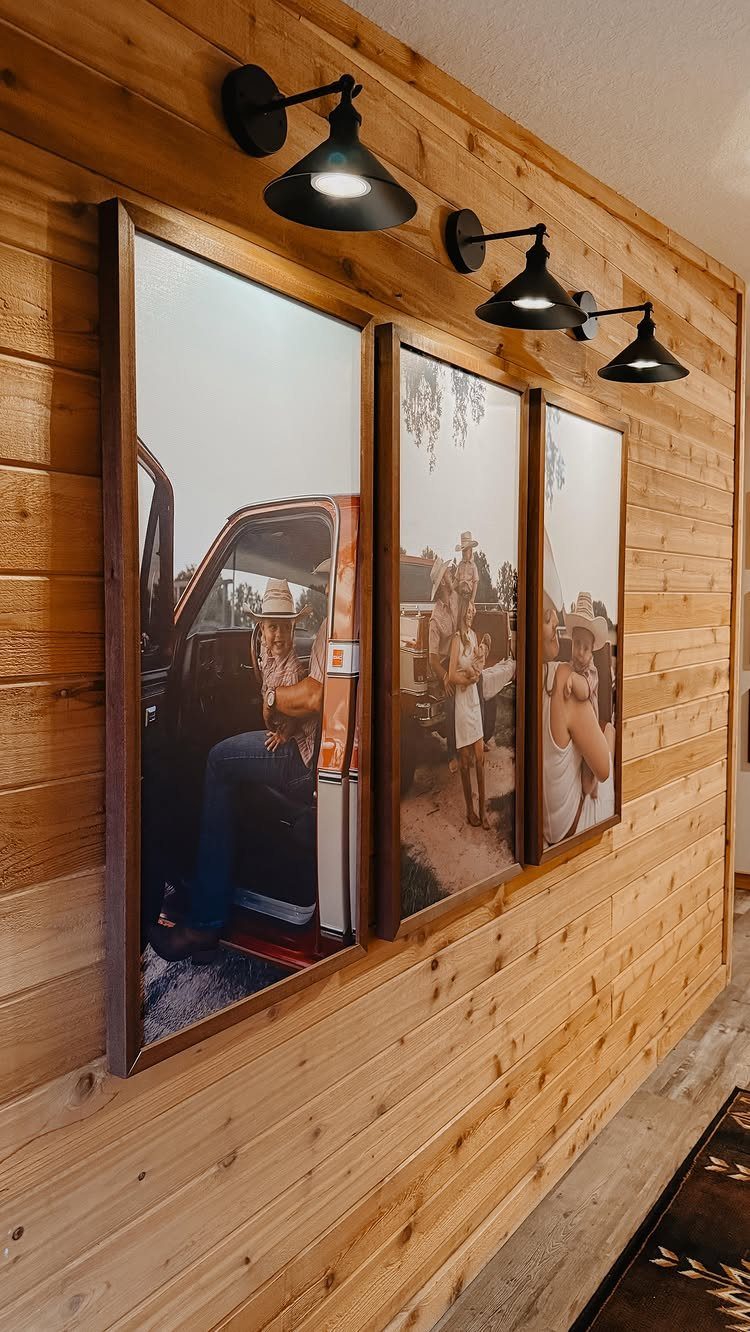 12 Modern Farmhouse Wall Decor Ideas for Living Room 7 Three large framed family photos on a wooden wall with black sconce lighting.