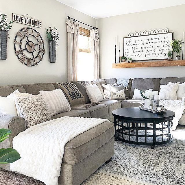 12 Modern Farmhouse Wall Decor Ideas for Living Room 13 Living room with grey sectional sofa and farmhouse style wall decor and wooden clock.